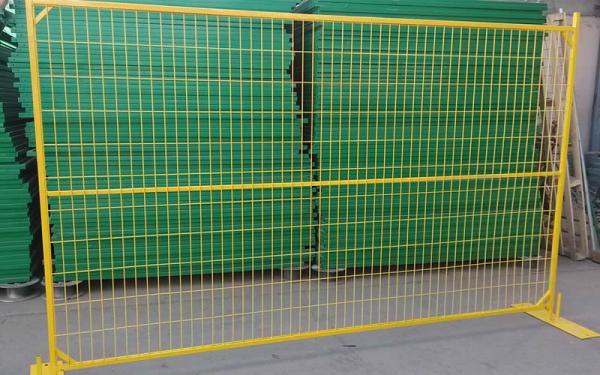 A Canada type temporary fencing on the ground with several green panels behind of it.